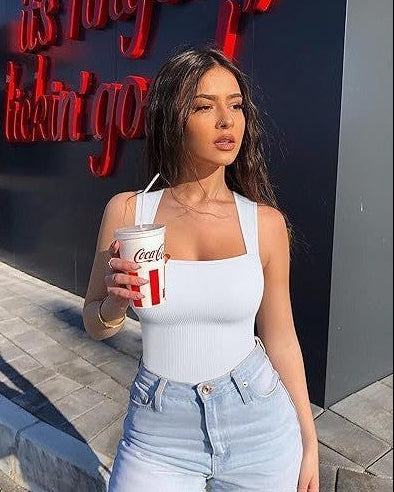 Woman holding a Coca-Cola cup in front of a store with red neon signs.