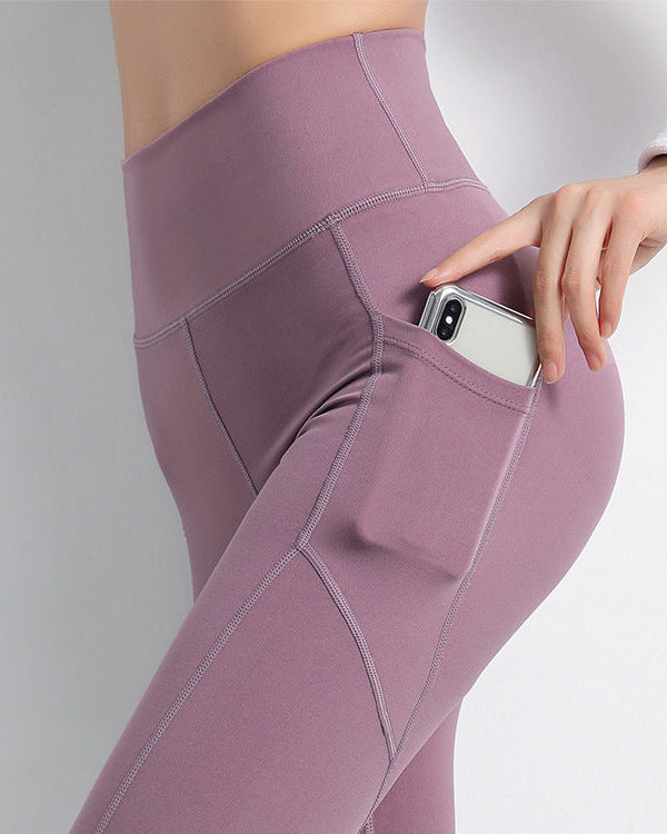 Purple leggings with a pocket holding a phone on a gray background