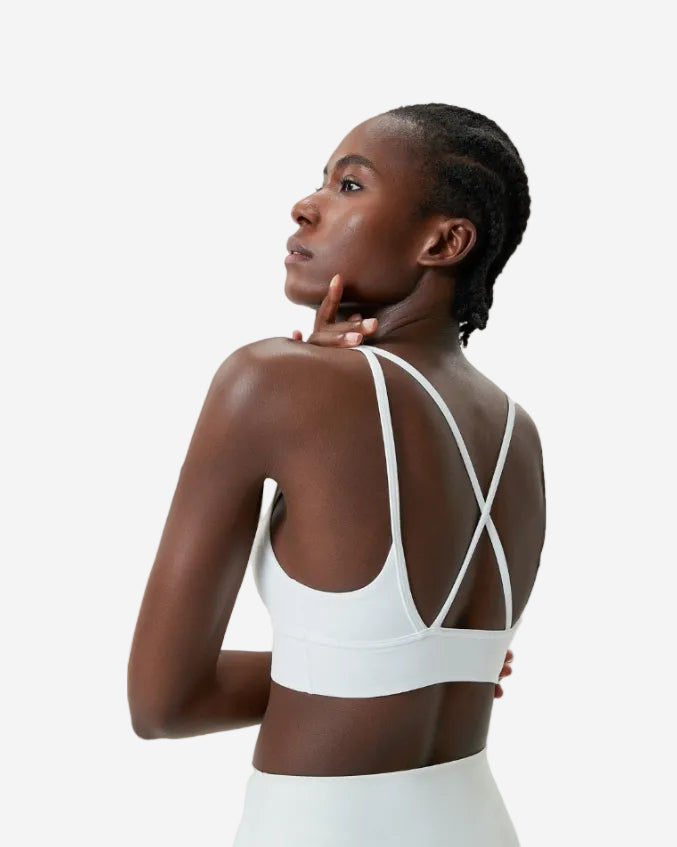 Woman wearing a white sports bra and shorts set on a light gray background