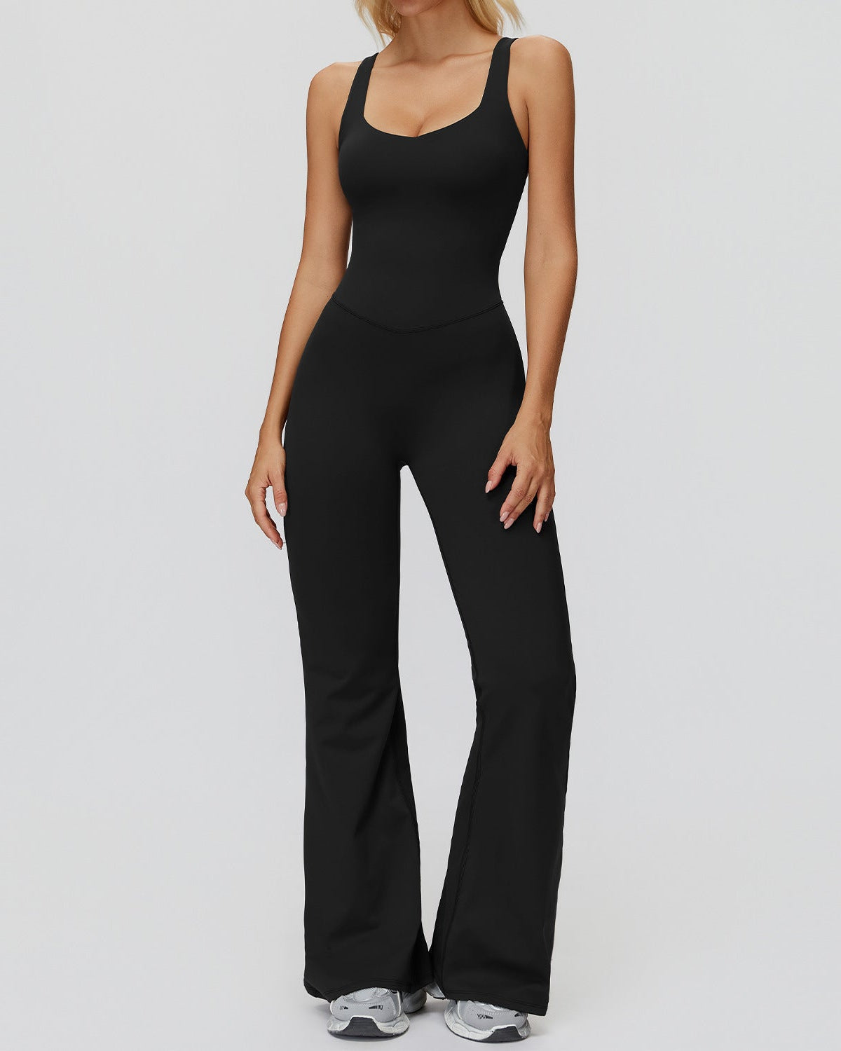 Person wearing a black jumpsuit on a plain background