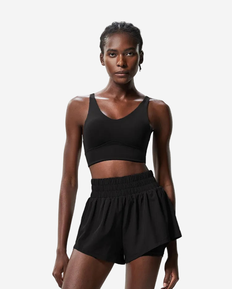 Woman wearing a black sports bra and shorts set, shown from front and back on a light gray background.