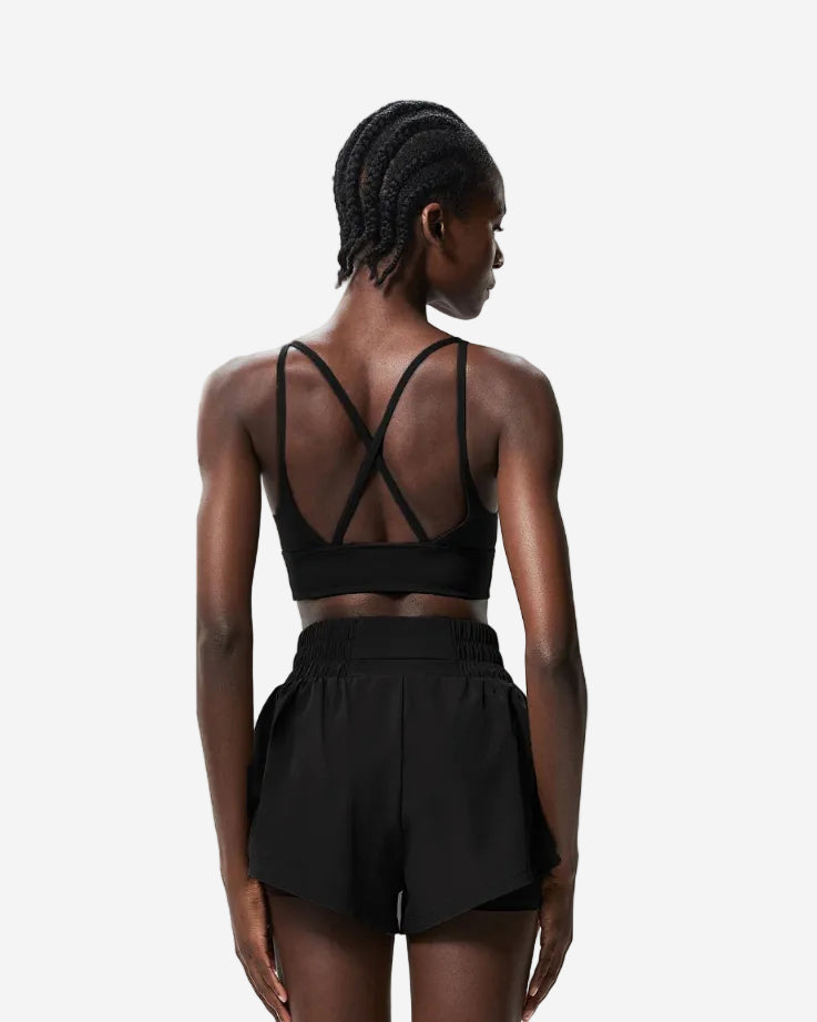 Woman wearing a black sports bra and shorts set, shown from front and back on a light gray background.